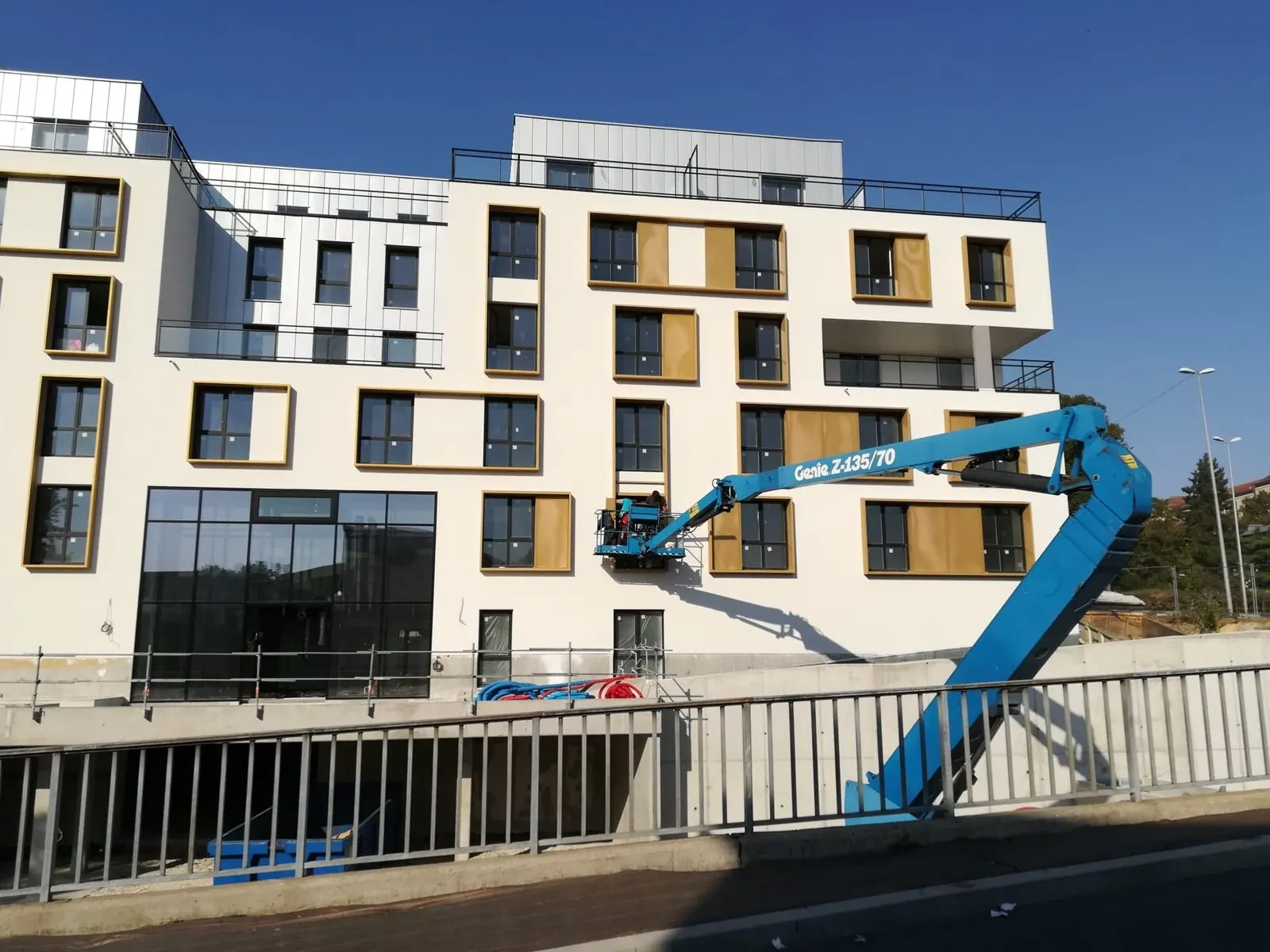 Clôture en acier gris clair à barreaudage vertical sur le mur de soutènement d'une résidence, nacelle en arrière-plan